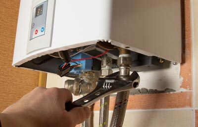 Boiler engineer reparing a gas bombi boiler with a cresent